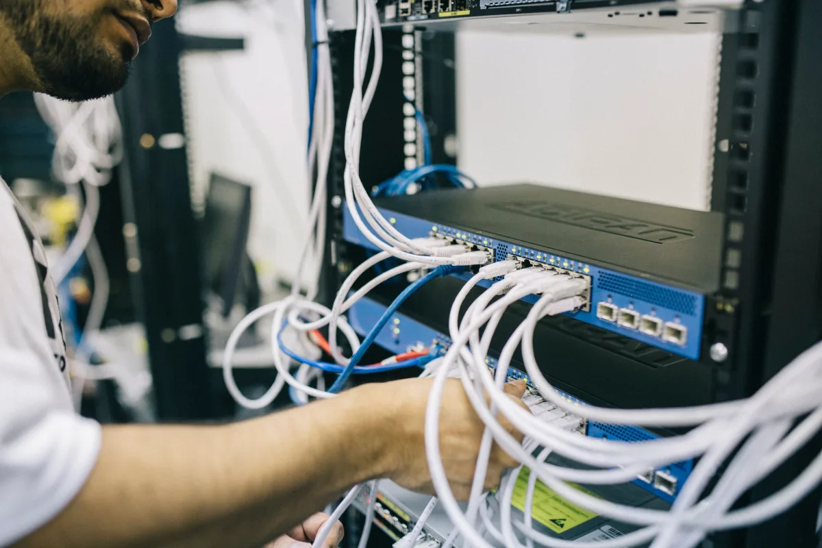 Techník prepojuje sieťové prvky v racku dátového centra (Pexels)